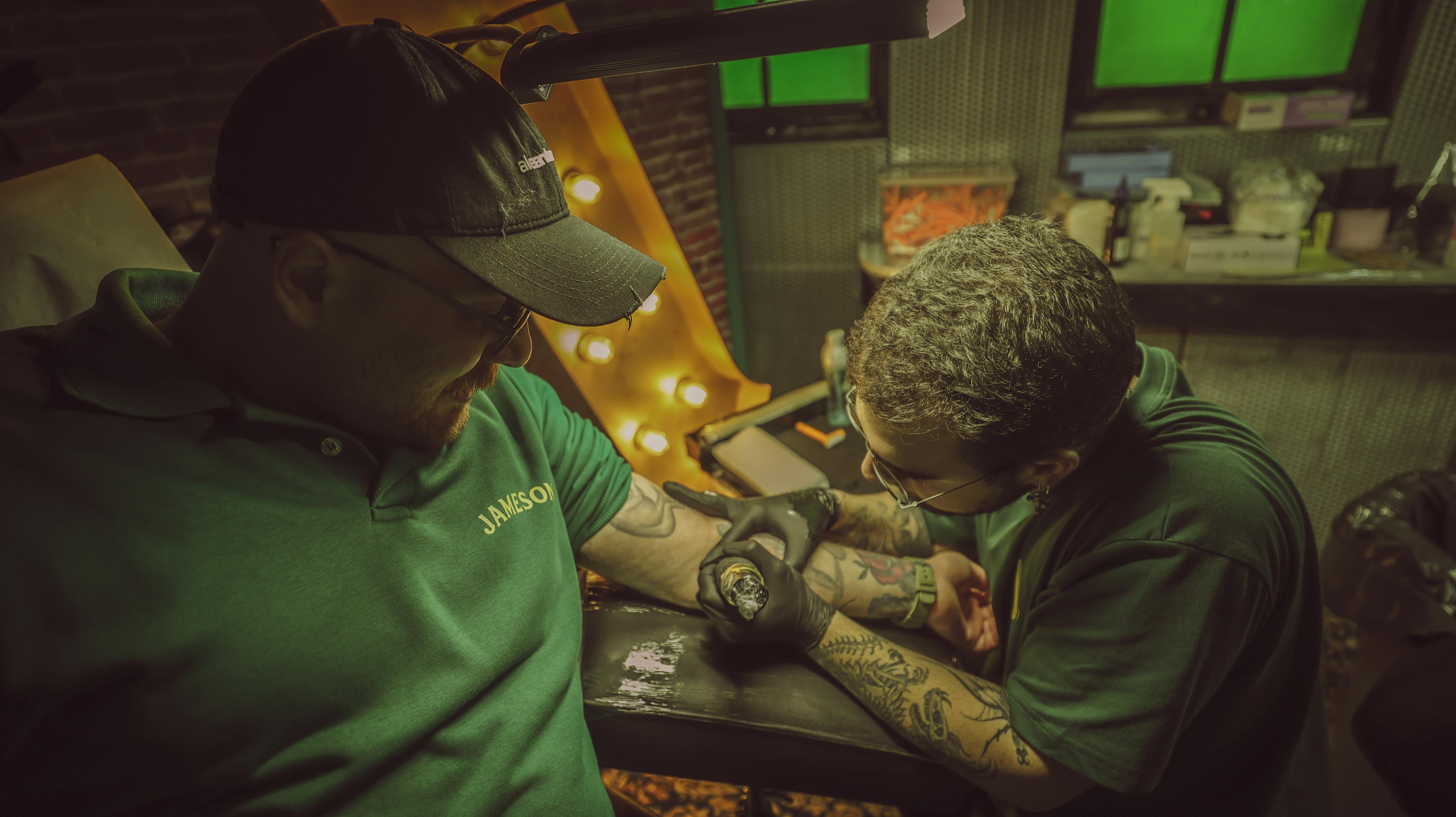 Reunion — Chris tattooing under marquee letters